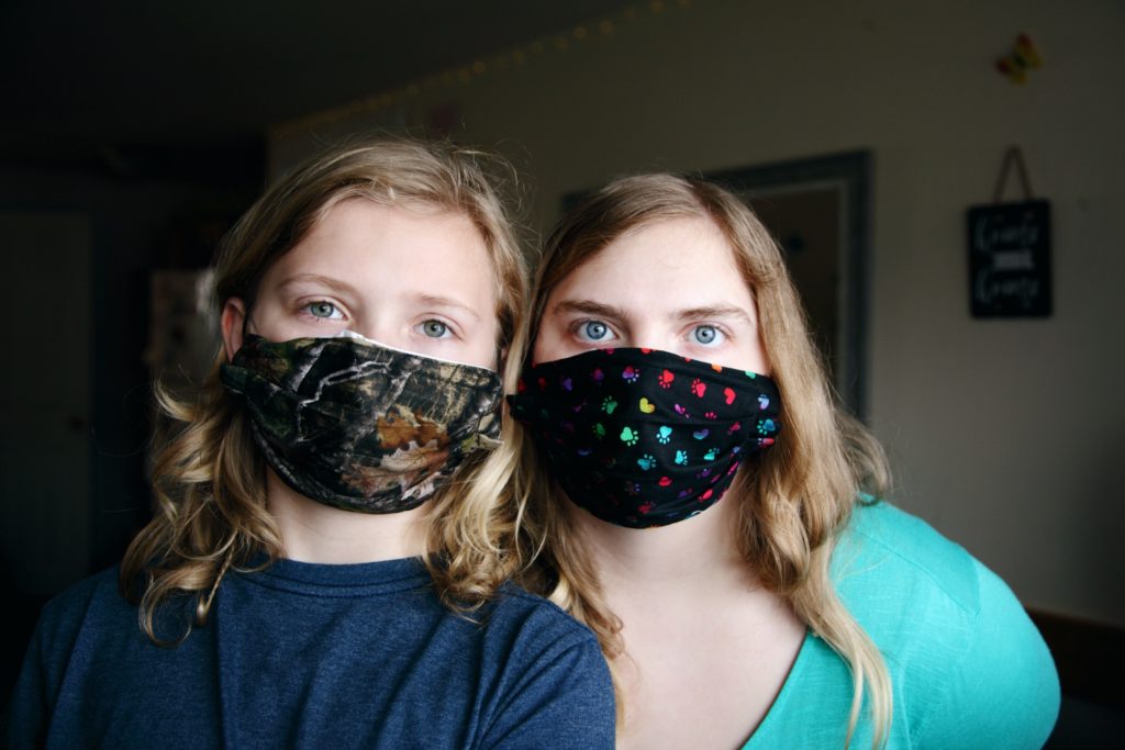 Two ladies covering their faces with a mask.