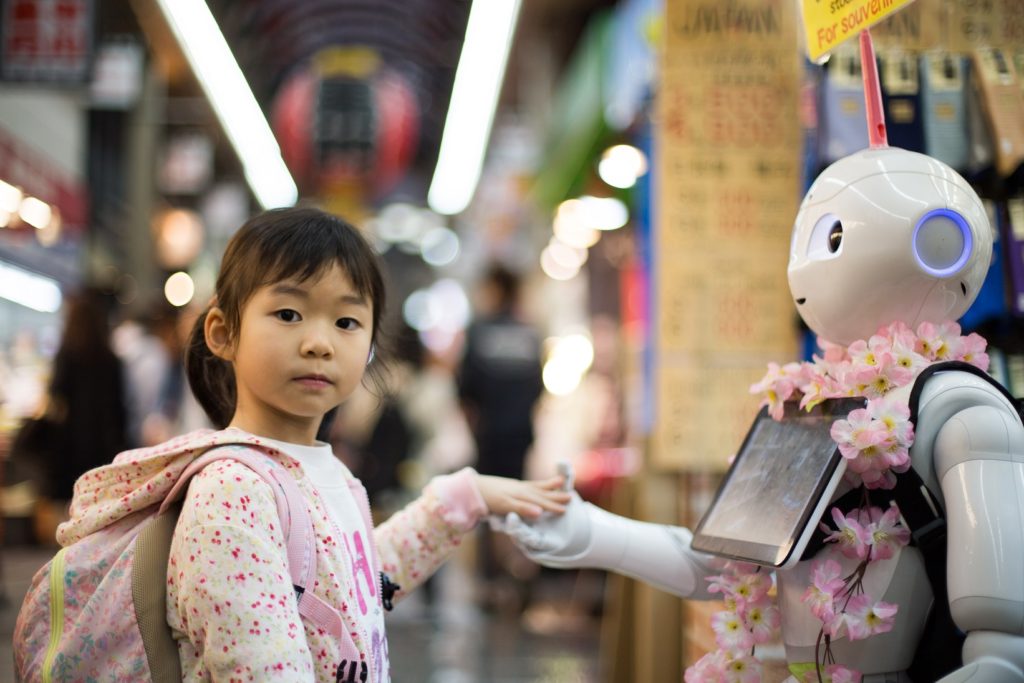 ロボットと手を取り合いこちらを見る少女