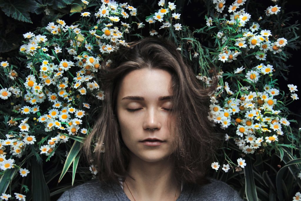 A woman with closed eyes amongst white flowers
