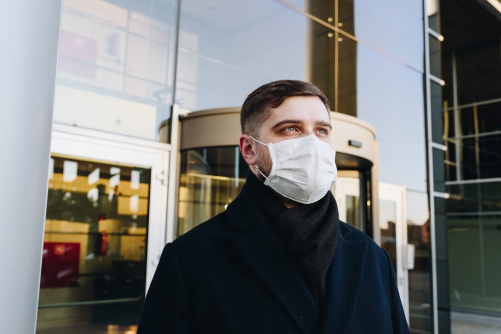 マスクをしている建物前の男性