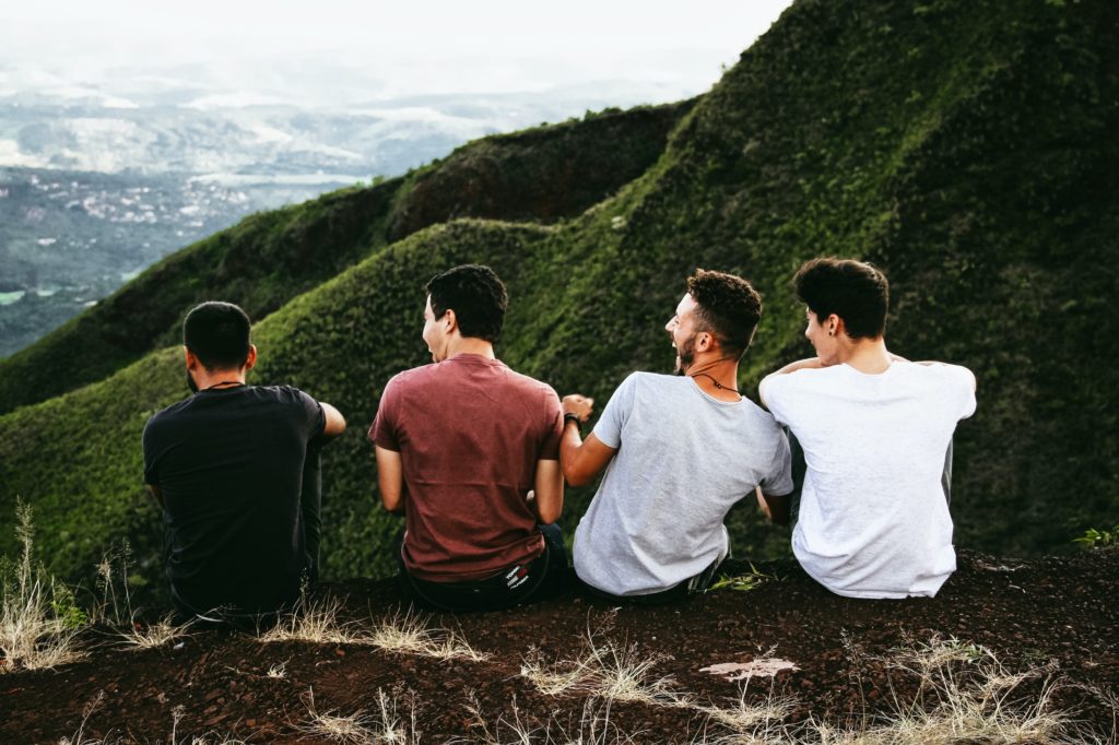 丘の上で肩を並べて座っている男性たち