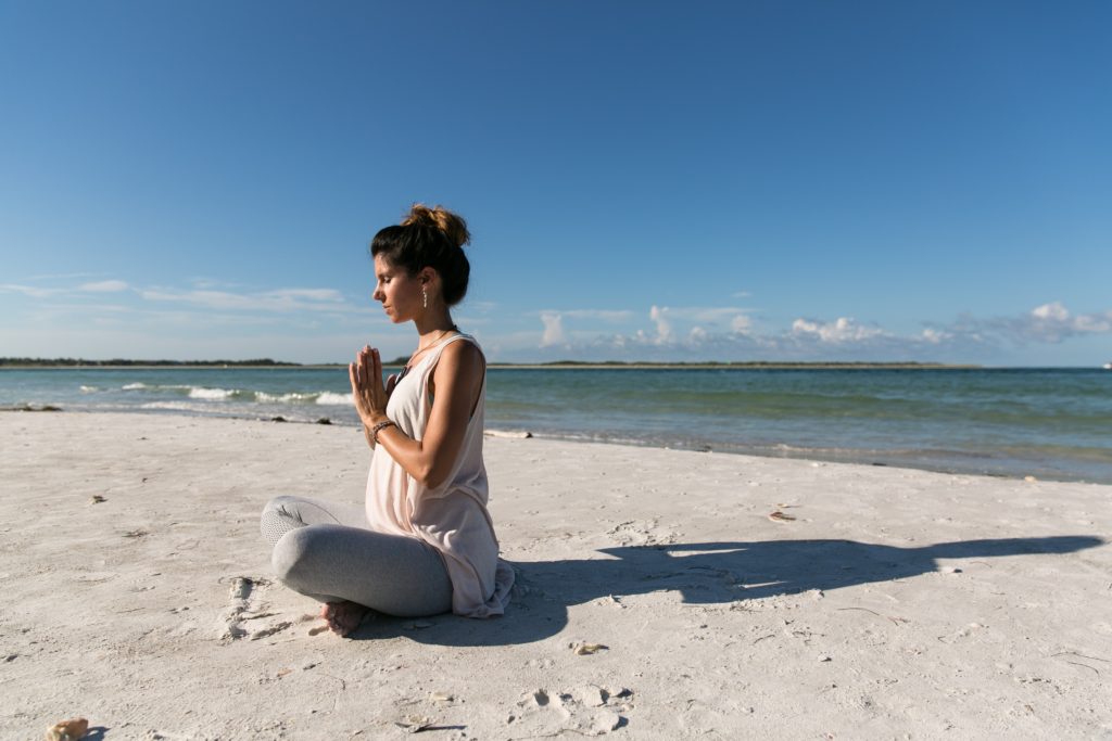 海辺で座って呼吸する女性