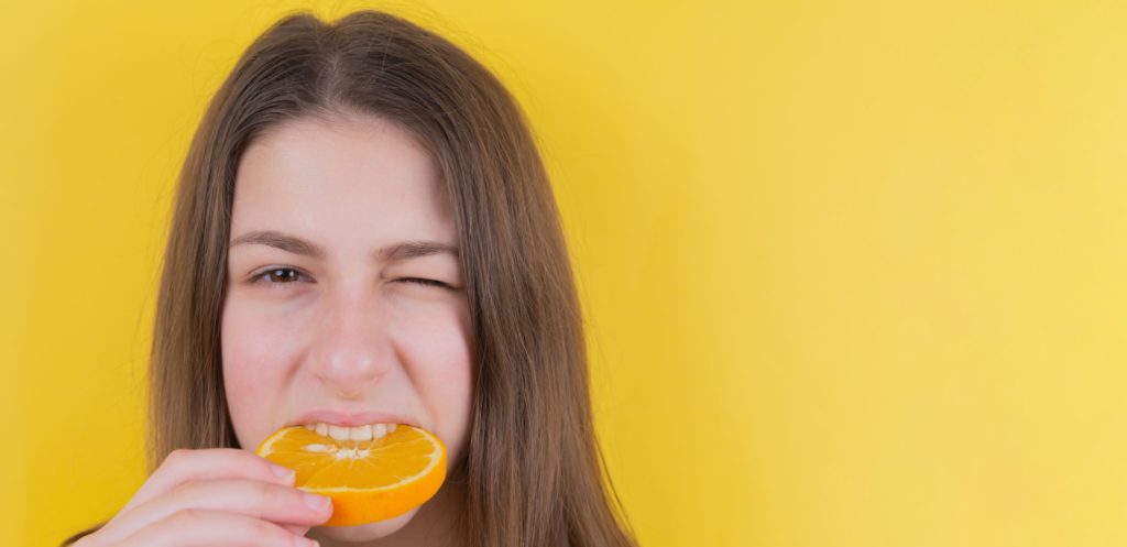 オレンジを噛んでいる女性