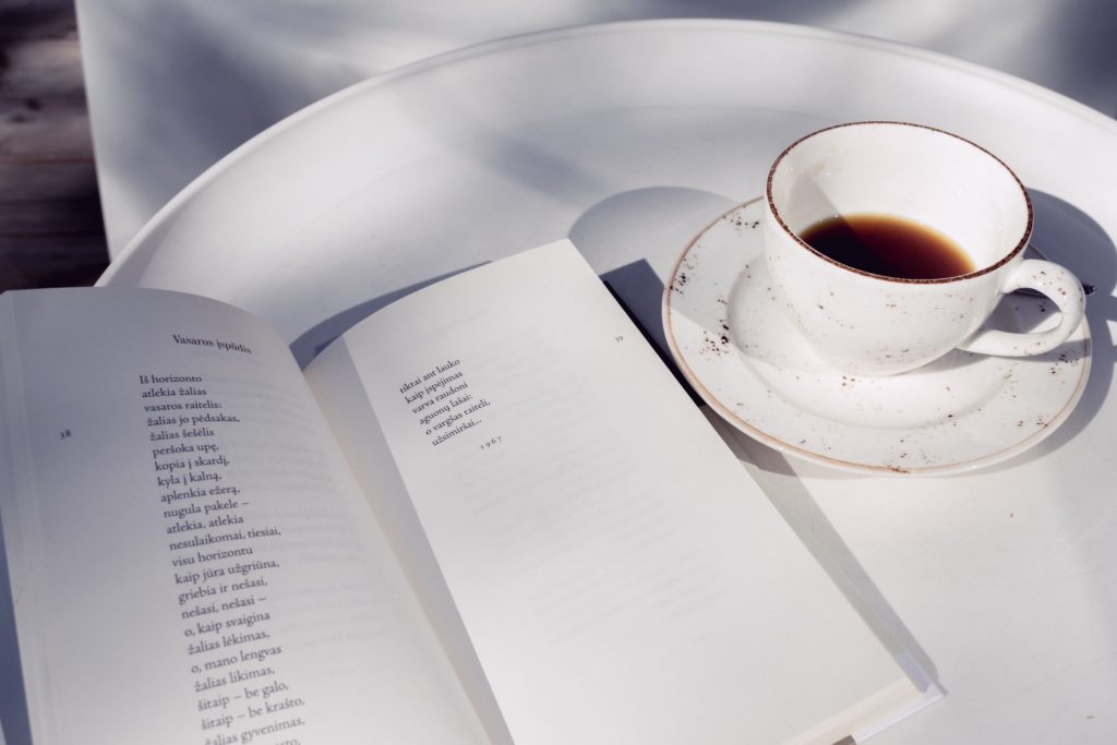 A cup of coffee and a book of poetry on a table