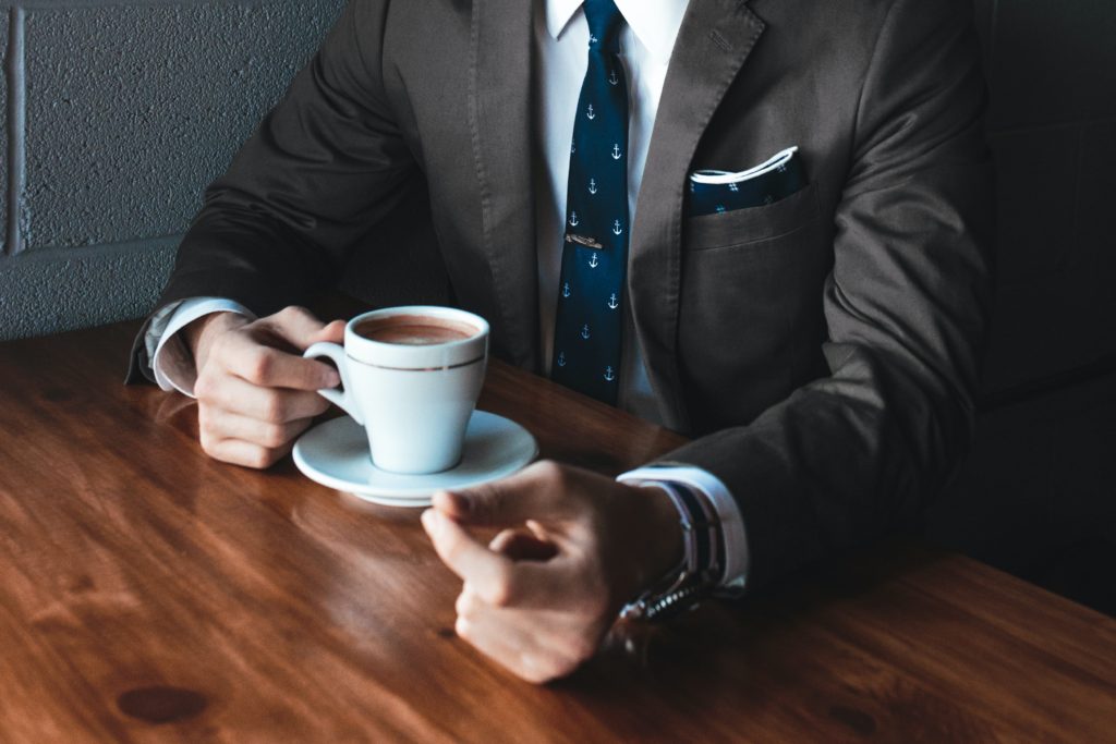 コーヒーを飲みながら話しているスーツの男