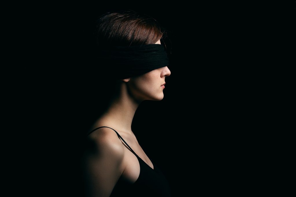 Woman with a blindfold against a black backdrop