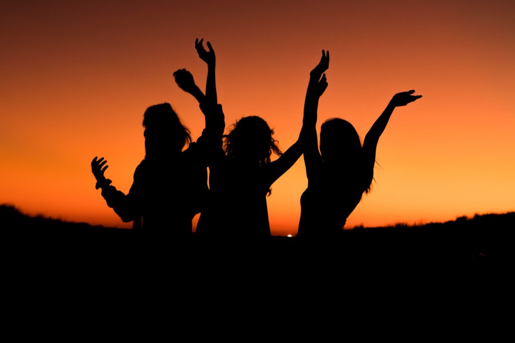Three women dancing in the sunset