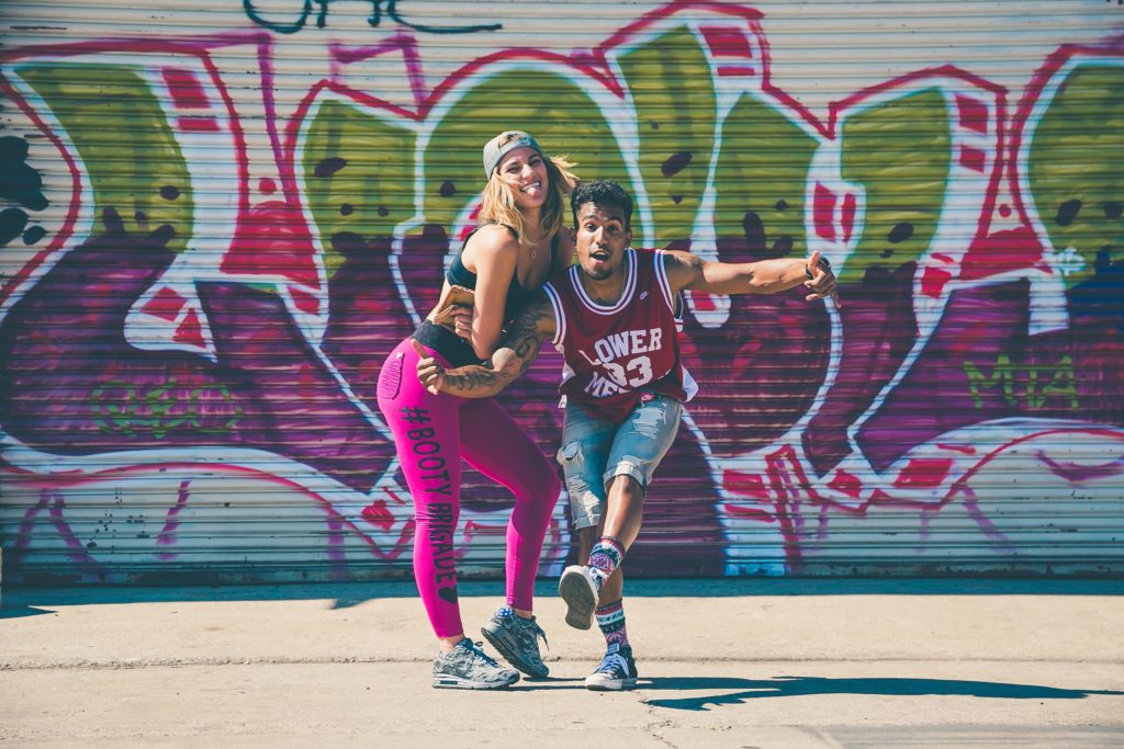 A man and a woman dancing together in front of graffiti