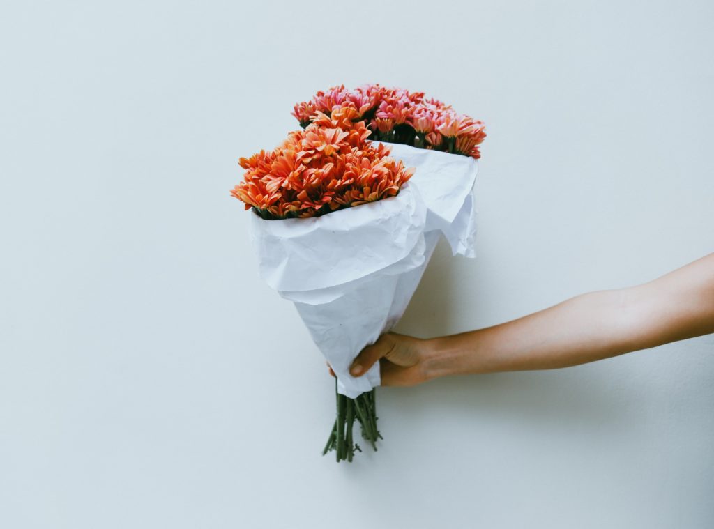 Person holding bouquets of orange flowers