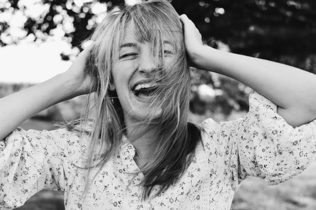 Black and white image of woman laughing with her hands to her head