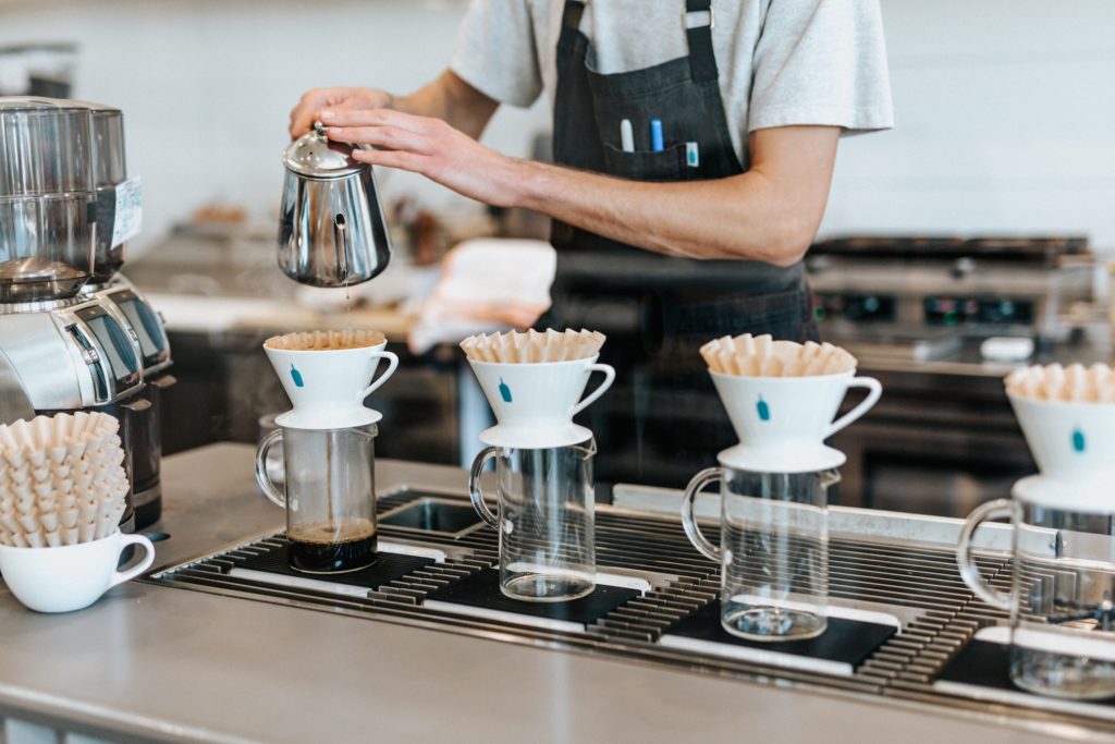 A barista serving pour-over coffee at a cafe