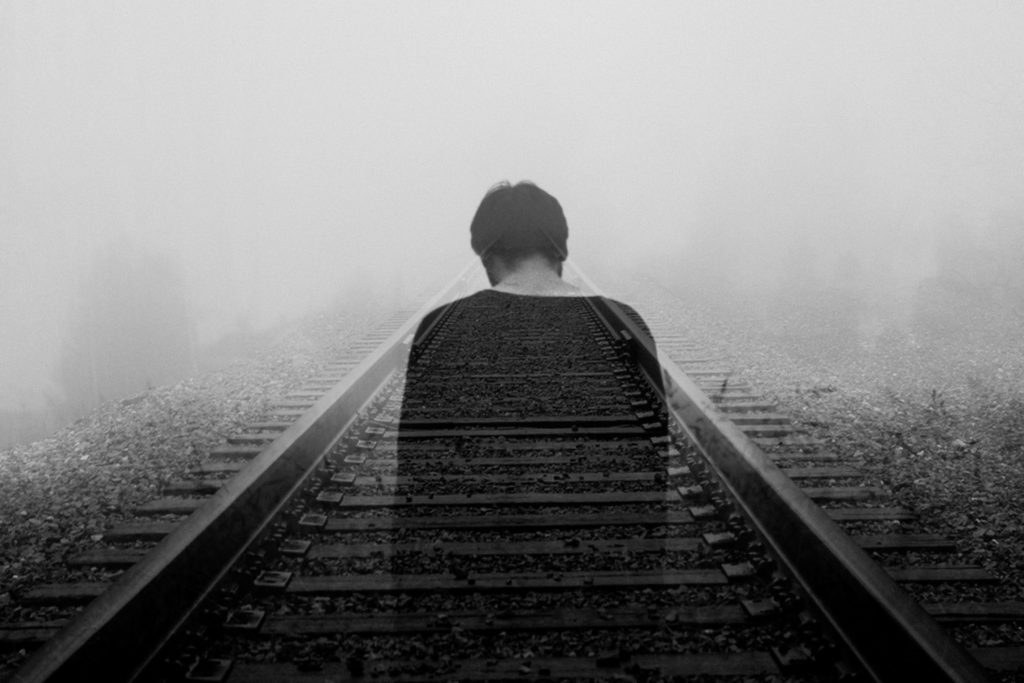 A man walking on the railroad in a depressed state