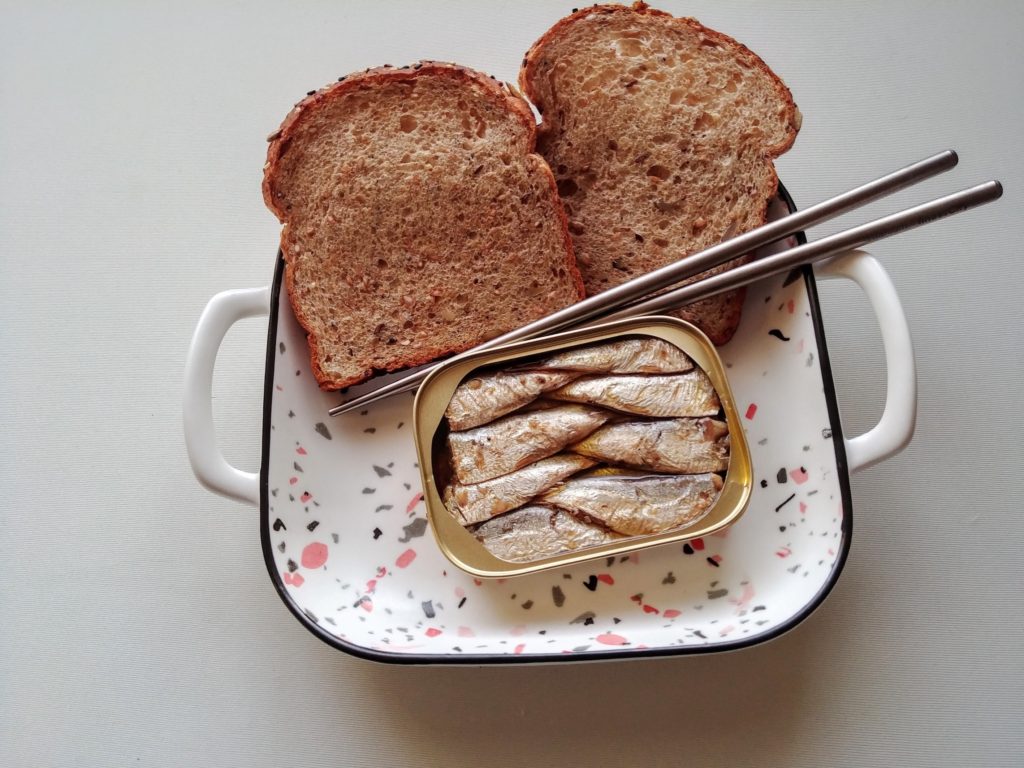 Toast and sardines on a plate with chopsticks