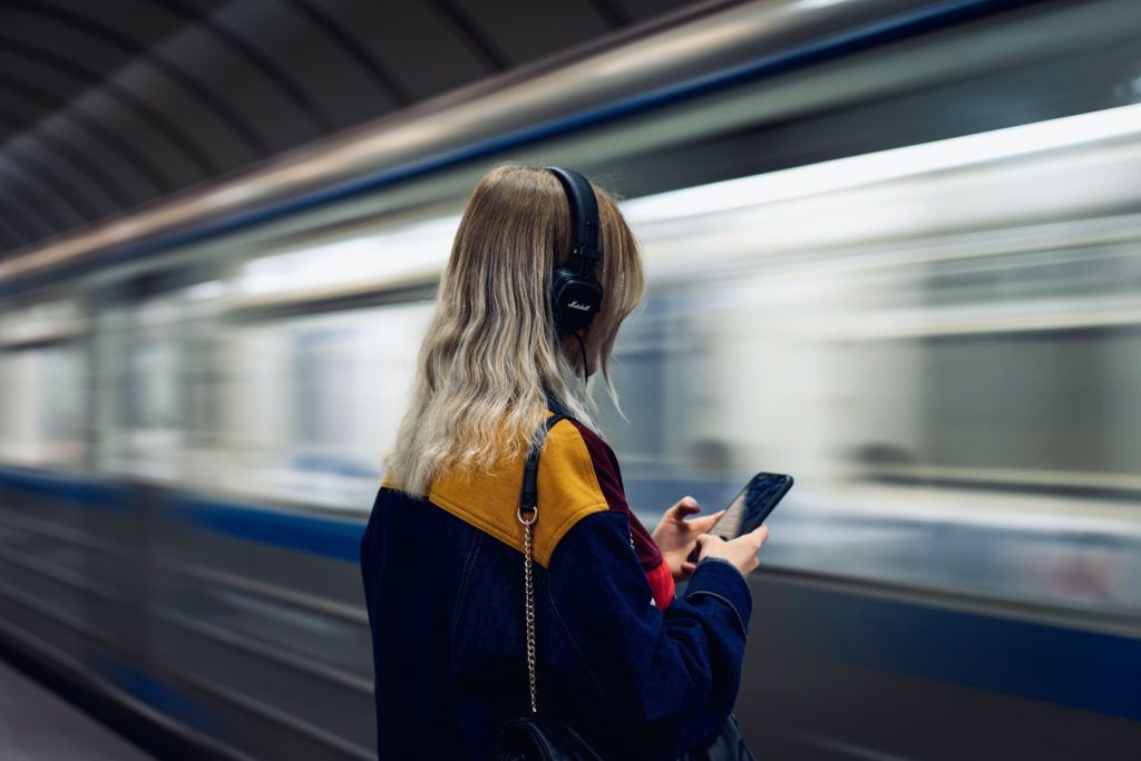Woman in black jacket holding a smartphone with headphones on