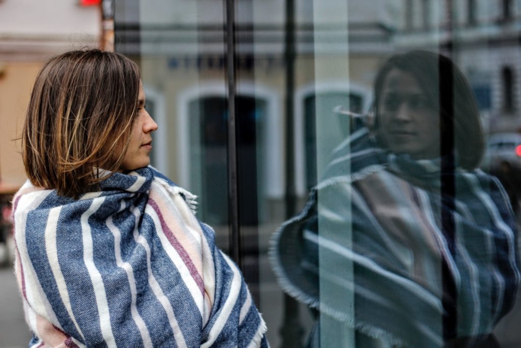 A woman staring at her reflection in a window