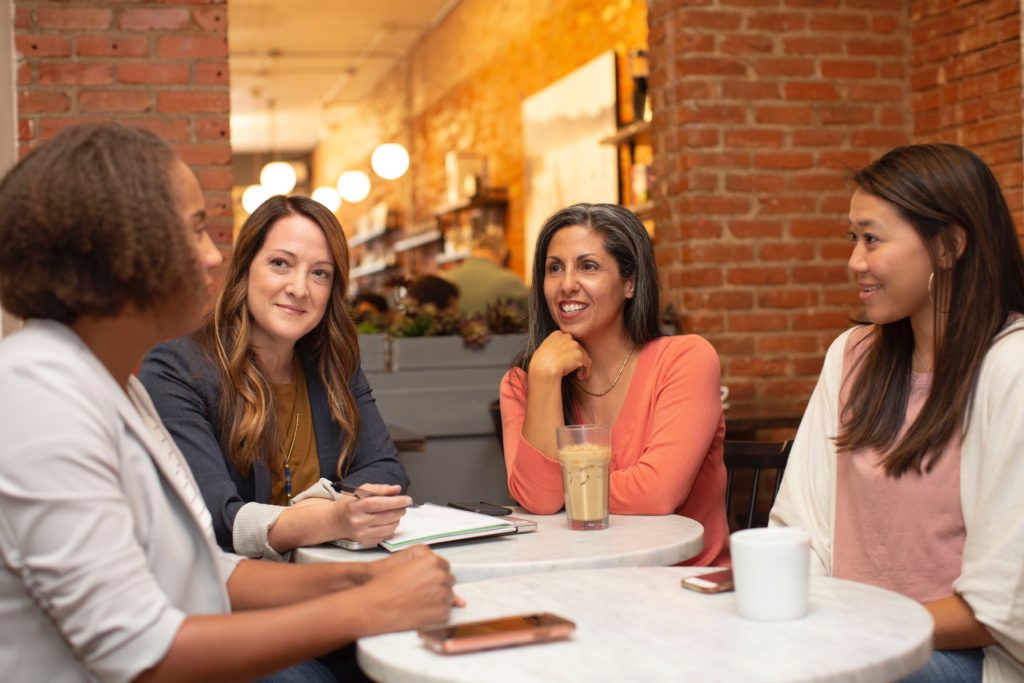 Women surrounging a table and talking at a cafe