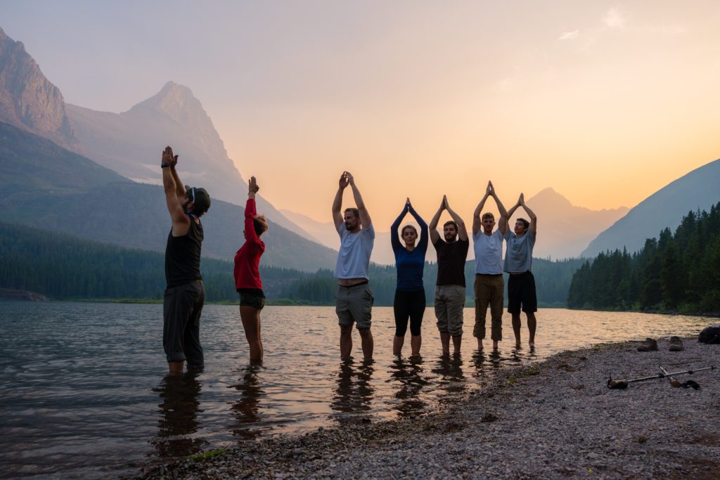 A group of people participating in a yoga pose out in nature.