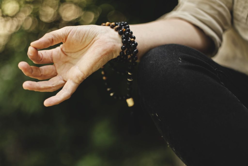 A person meditating with beads around their wrist