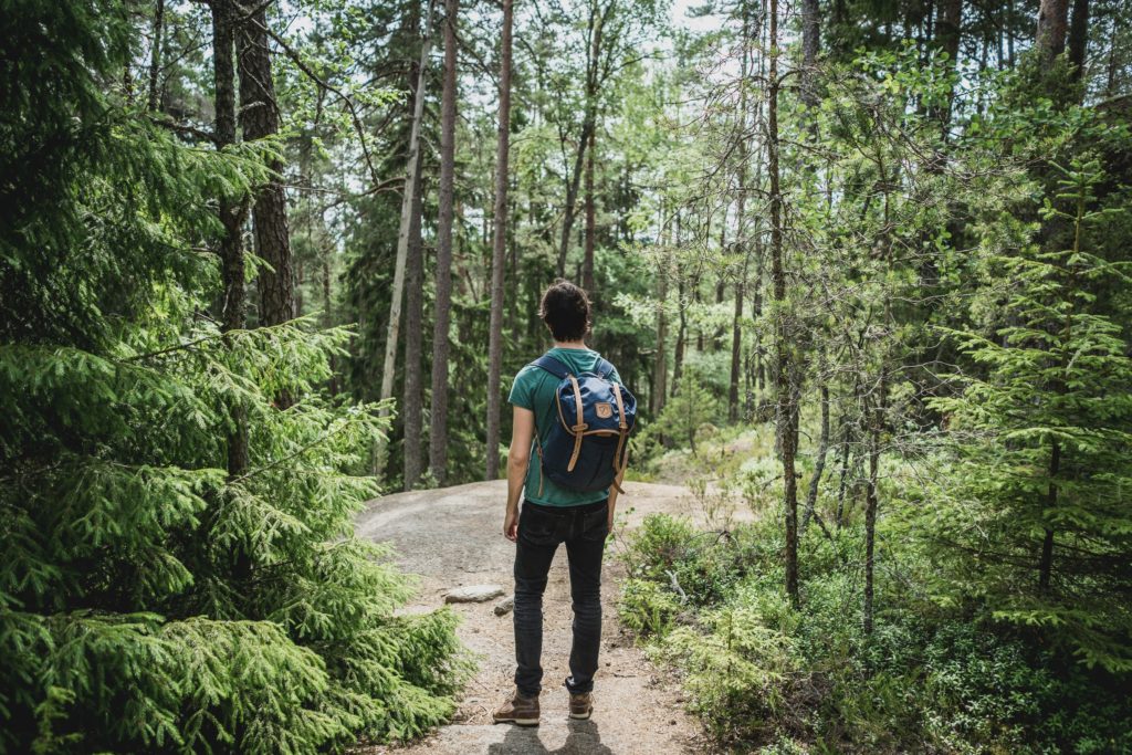 A man standing alone in a forest with a backpack