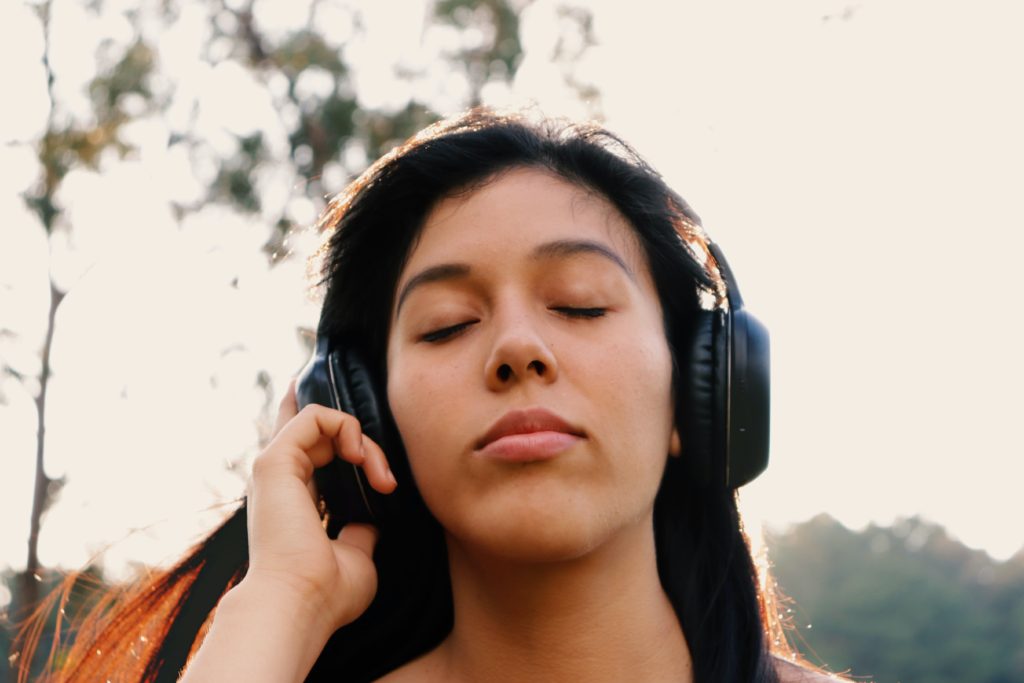 A woman listening to her headphones as she closes her eyes.